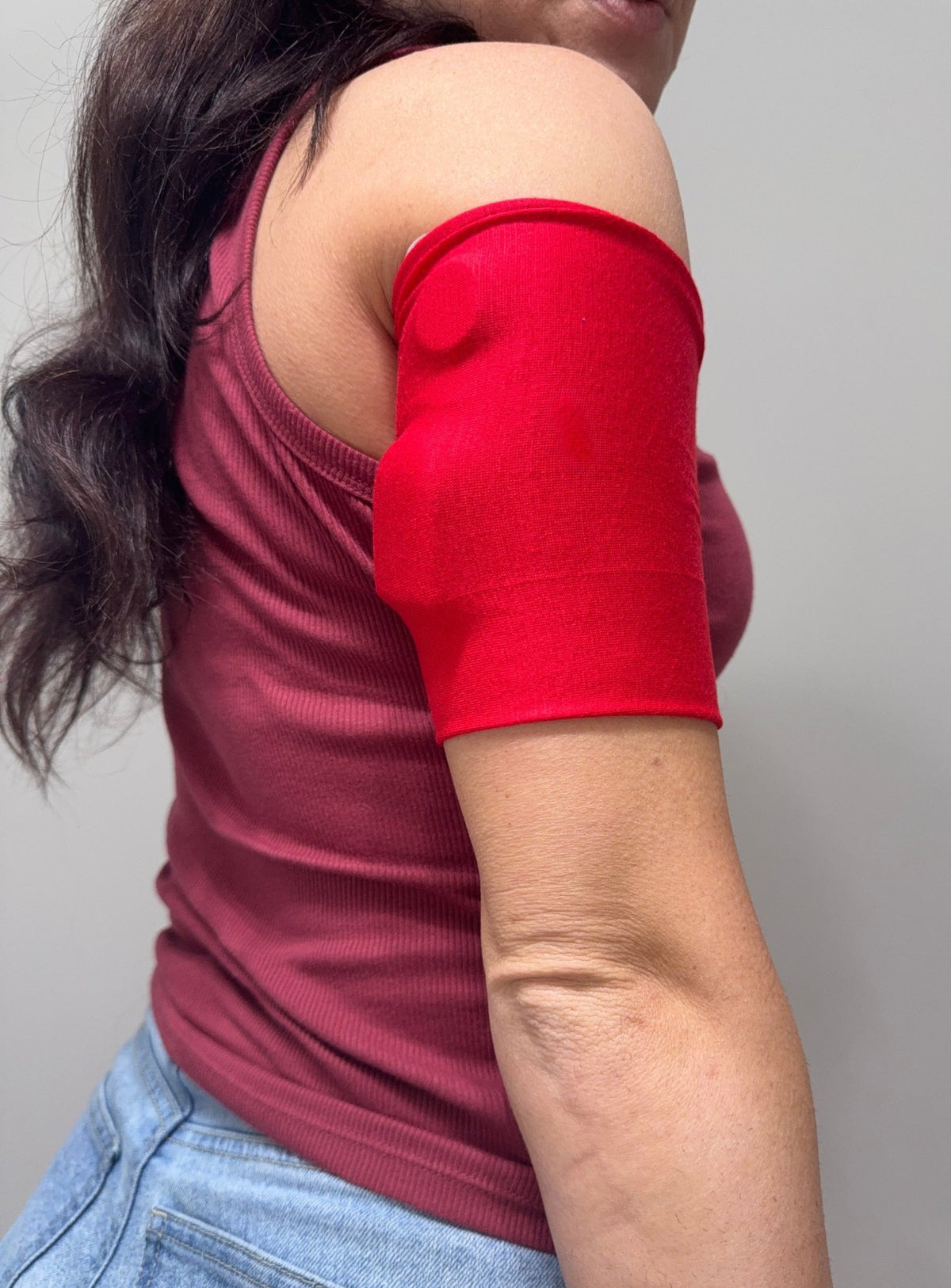 Soft cotton-feel pod band in Red worn on the upper arm over a pod