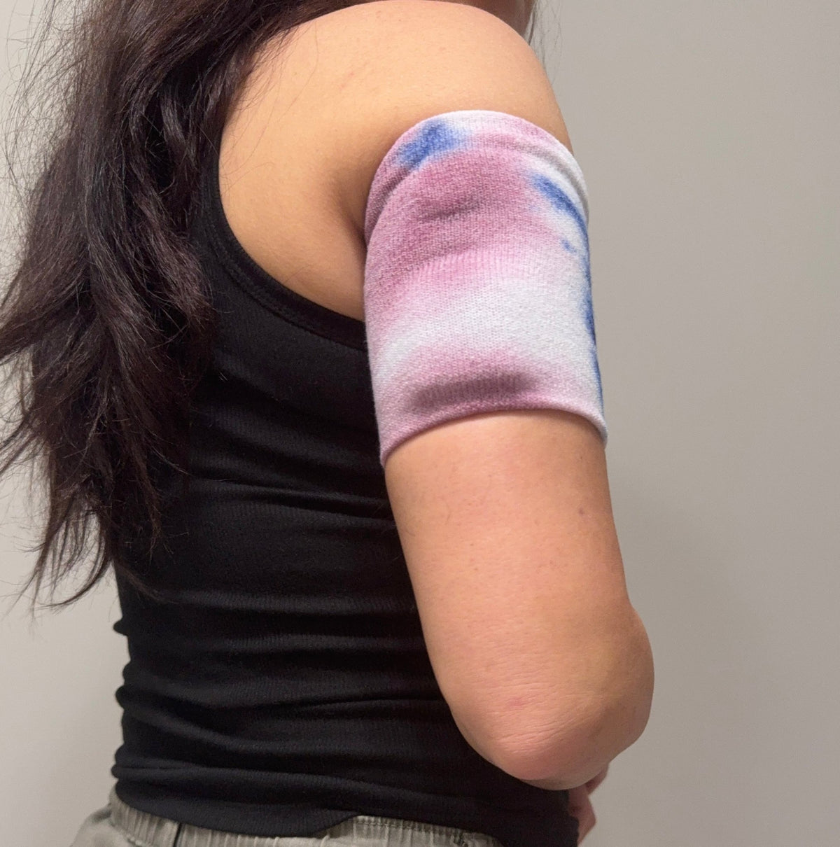 Sweater knit pod band in Sunset Ombré, pink, white and blue, worn on the upper arm over a pod