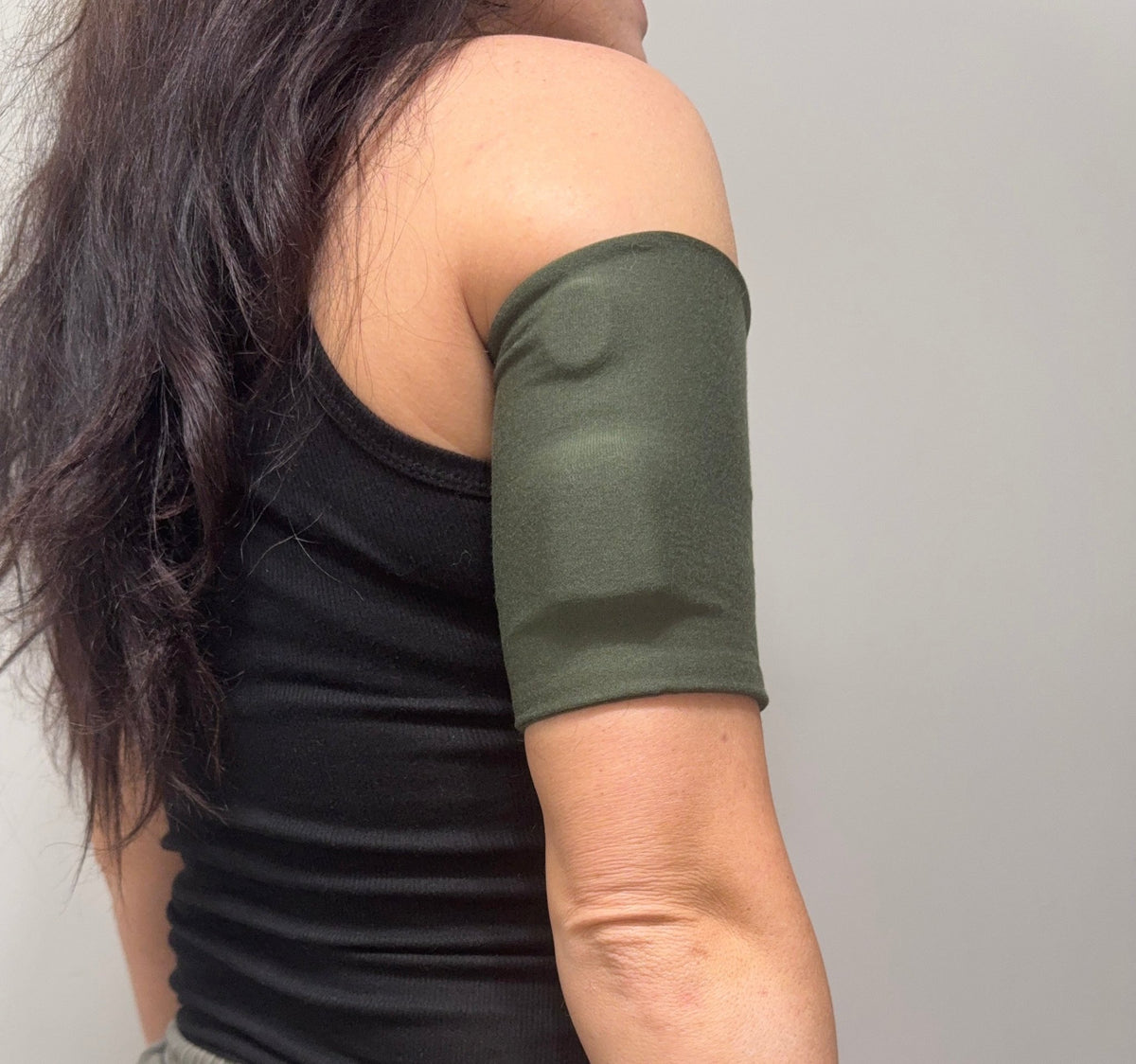 Soft cotton-feel pod band in Olive worn on the upper arm over a pod
