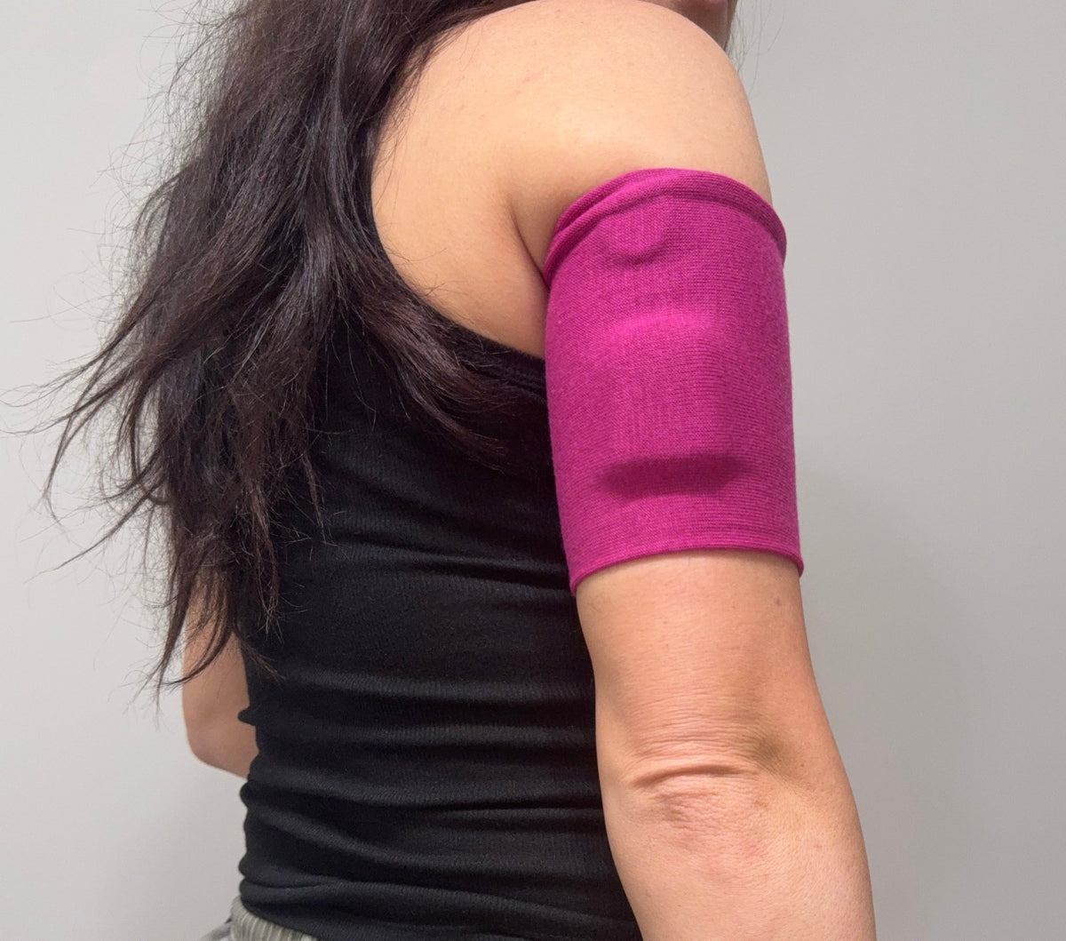 Cozy pod band in Magenta worn on the upper arm over a pod