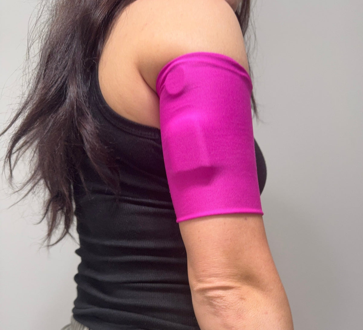 Smooth knit pod band in Hot Pink worn on the upper arm over a pod
