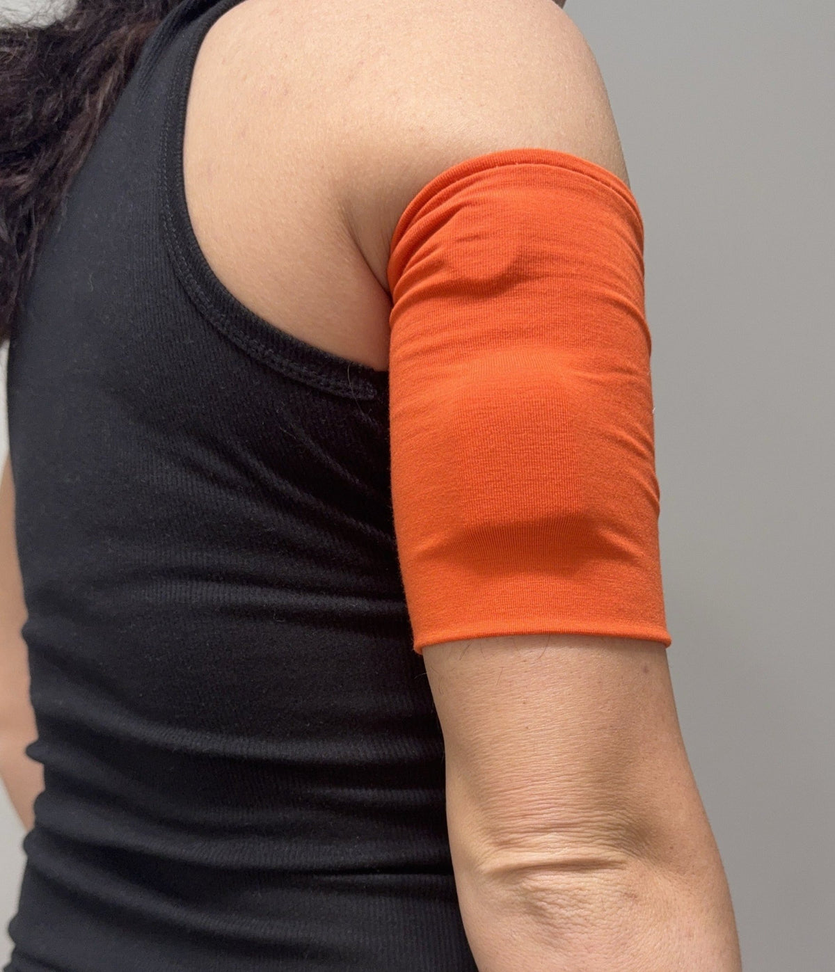 Cozy pod band in Orange worn on the upper arm over a pod