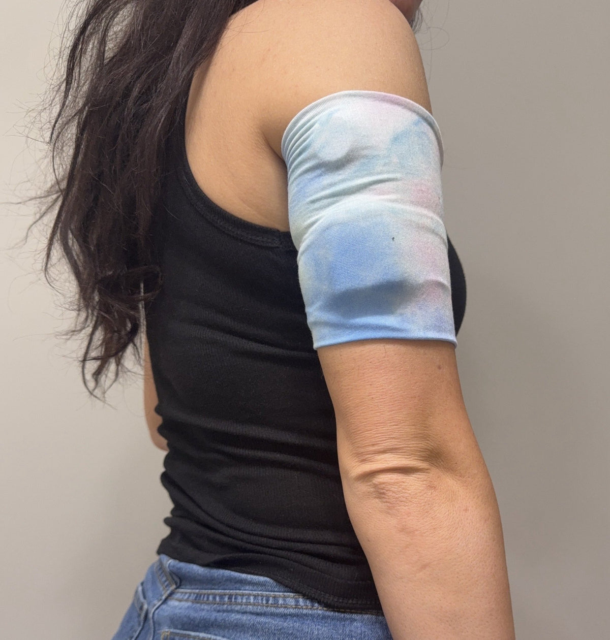 Soft cotton-feel pod band in pink, blue and white tie dye worn on the upper arm over a pod